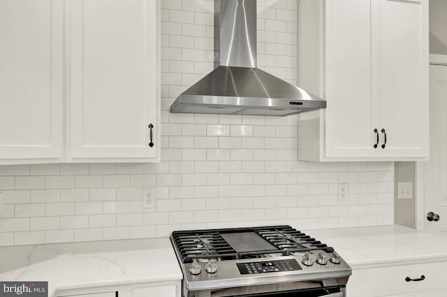 kitchen with stainless steel stove, white cabinetry, wall chimney exhaust hood, and light stone counters