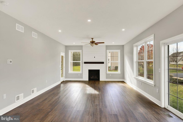 unfurnished living room featuring a fireplace, dark hardwood / wood-style flooring, ceiling fan, and a healthy amount of sunlight