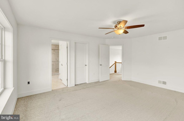 unfurnished bedroom with ensuite bath, ceiling fan, and light colored carpet