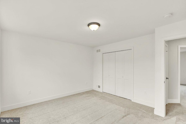 unfurnished bedroom with light carpet and a closet