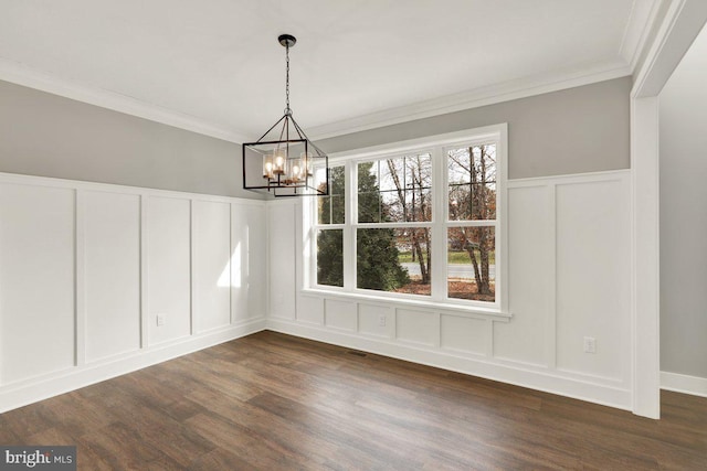 unfurnished dining area with dark hardwood / wood-style floors, ornamental molding, and a chandelier