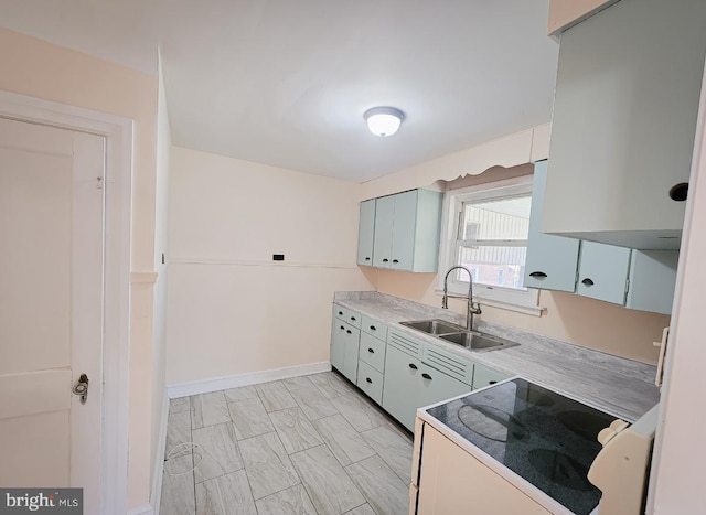 kitchen with stove, white cabinetry, and sink