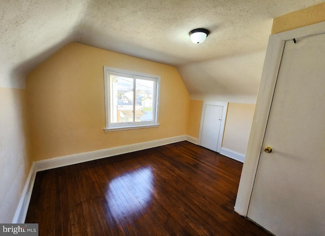 bonus room featuring a textured ceiling, vaulted ceiling, and dark wood-type flooring