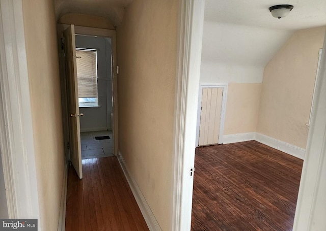 corridor with hardwood / wood-style flooring and lofted ceiling