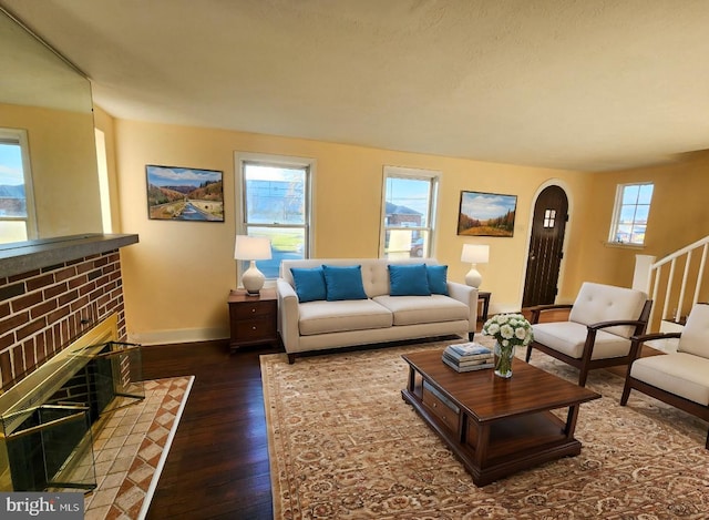 living room with plenty of natural light, dark hardwood / wood-style flooring, and a brick fireplace