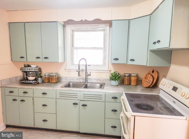 kitchen with white range with electric cooktop, light tile patterned floors, sink, and green cabinetry