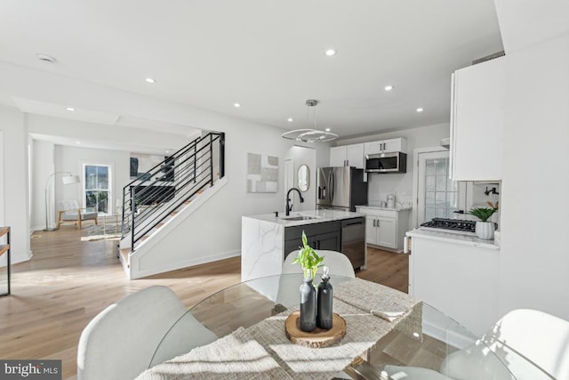 dining space with light hardwood / wood-style floors, a notable chandelier, and sink