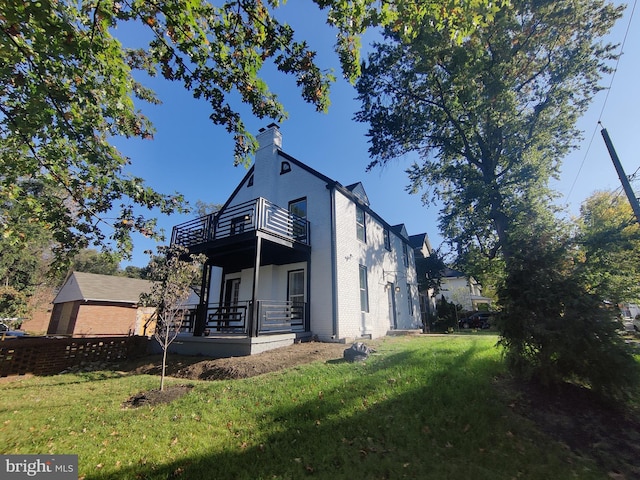 view of side of property featuring a lawn and a balcony