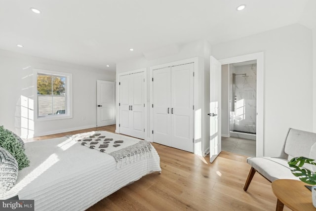 bedroom featuring multiple closets, ensuite bathroom, and light wood-type flooring