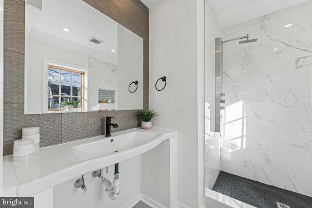 bathroom featuring a tile shower and sink