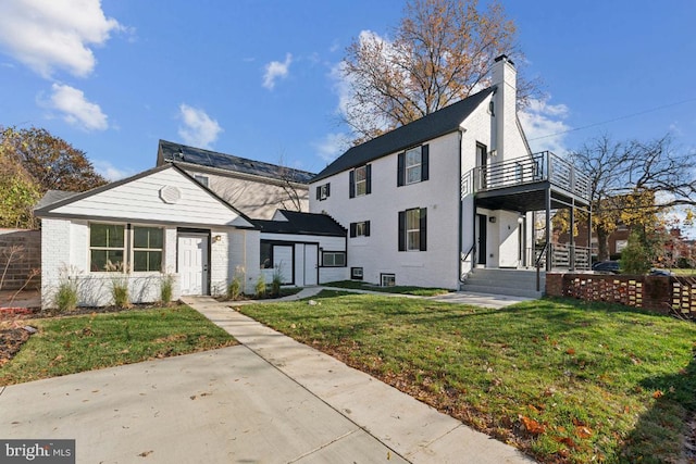 view of front of house with a balcony and a front lawn