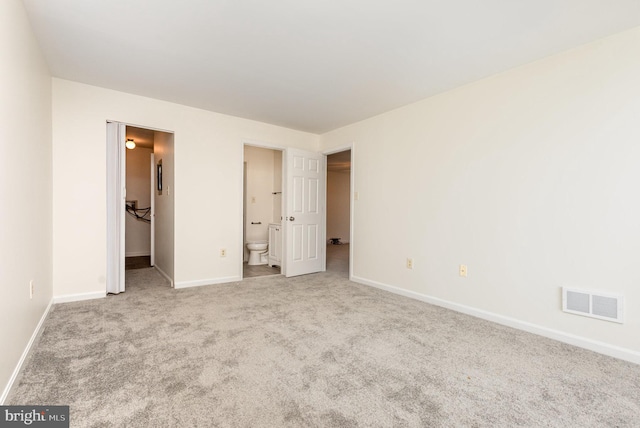 unfurnished bedroom featuring connected bathroom and light colored carpet