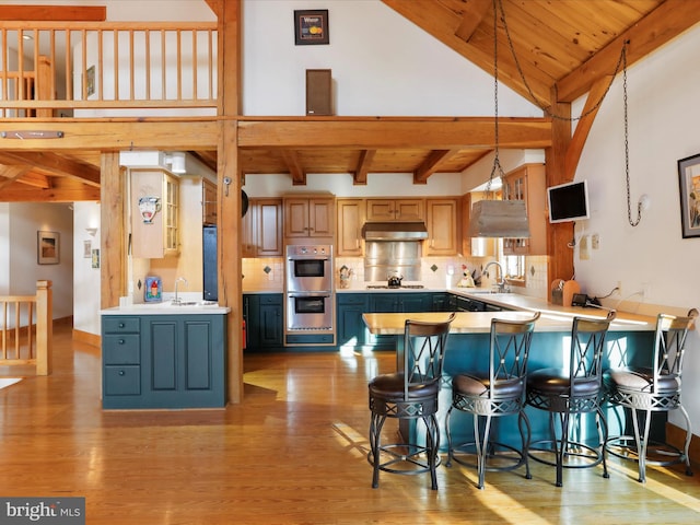 kitchen featuring pendant lighting, sink, gas stovetop, a kitchen bar, and kitchen peninsula