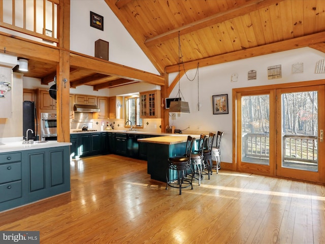 kitchen with hanging light fixtures, a breakfast bar area, oven, and beam ceiling