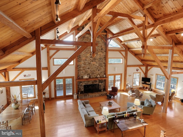 living room featuring wood ceiling, a stone fireplace, plenty of natural light, and light wood-type flooring