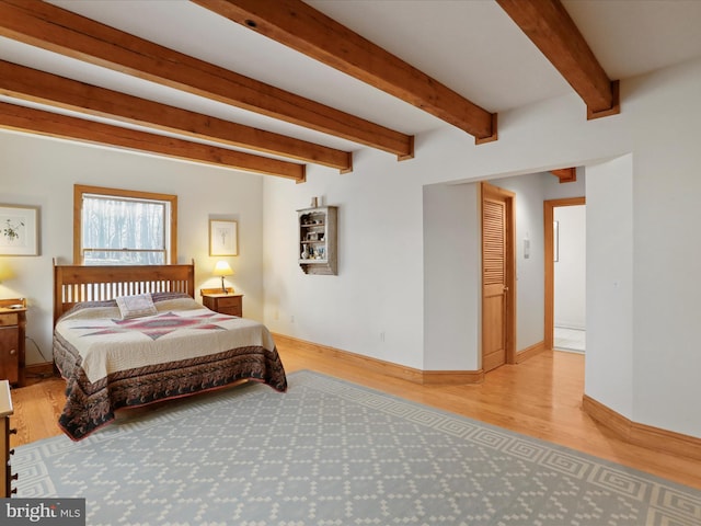 bedroom with beamed ceiling and light wood-type flooring