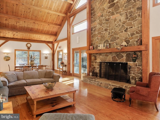 living room with a stone fireplace, wooden ceiling, beamed ceiling, and hardwood / wood-style flooring