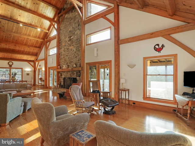 living room featuring plenty of natural light, wooden ceiling, light wood-type flooring, and a stone fireplace