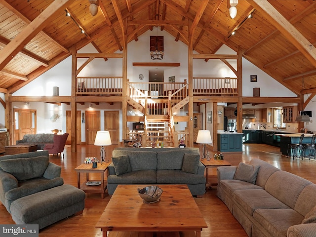 living room featuring beam ceiling, wooden ceiling, rail lighting, and light wood-type flooring