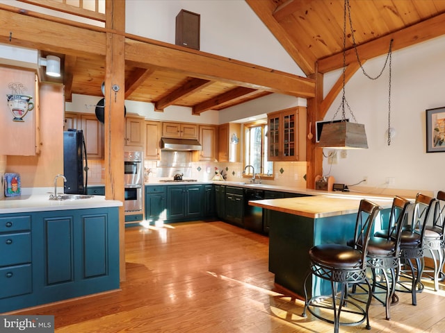 kitchen featuring wood ceiling, appliances with stainless steel finishes, beam ceiling, decorative light fixtures, and kitchen peninsula