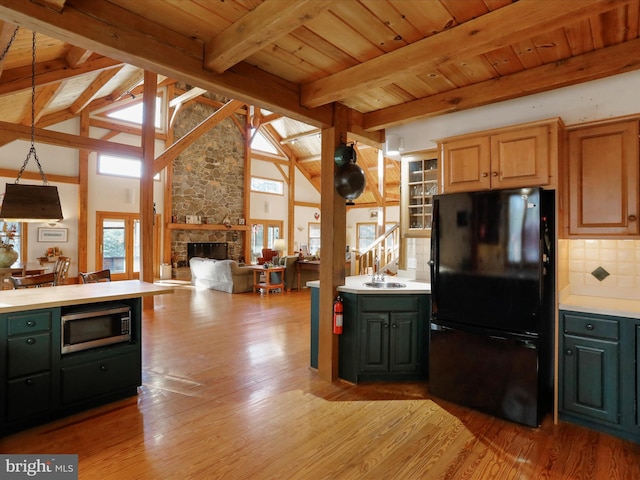 kitchen with black refrigerator, pendant lighting, sink, wood ceiling, and light hardwood / wood-style flooring