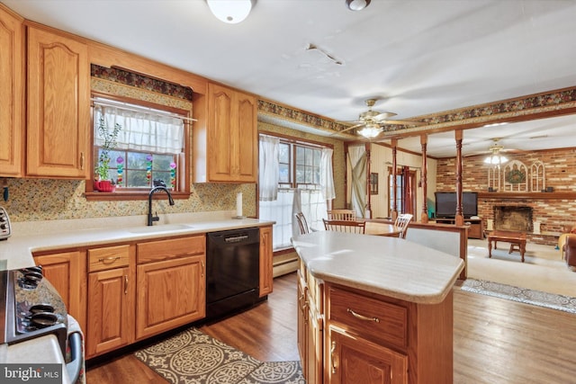 kitchen with a brick fireplace, sink, wood-type flooring, dishwasher, and a center island