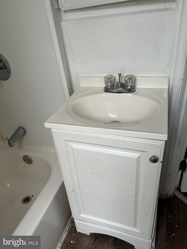 bathroom featuring hardwood / wood-style floors, vanity, and a tub to relax in