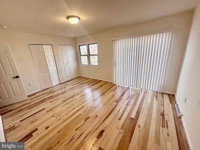 unfurnished bedroom with multiple closets and light hardwood / wood-style flooring