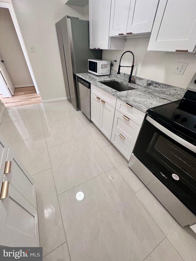 kitchen featuring light stone countertops, white cabinetry, appliances with stainless steel finishes, and sink