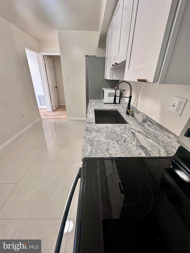 kitchen featuring sink, white cabinets, and light stone counters