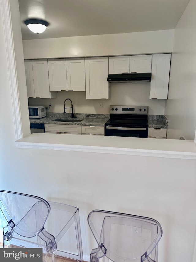 kitchen with electric stove, white cabinetry, and sink