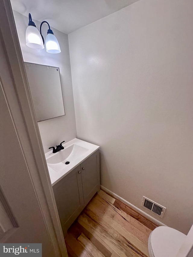 bathroom with hardwood / wood-style flooring, vanity, and toilet