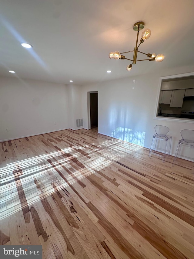 unfurnished living room with a notable chandelier and light wood-type flooring