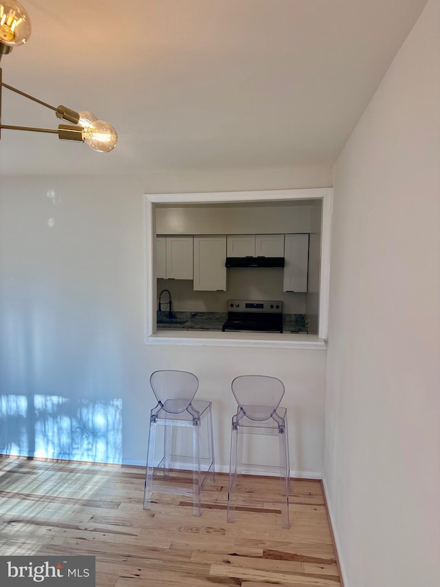 kitchen featuring white cabinetry, sink, light hardwood / wood-style floors, and stainless steel electric range oven