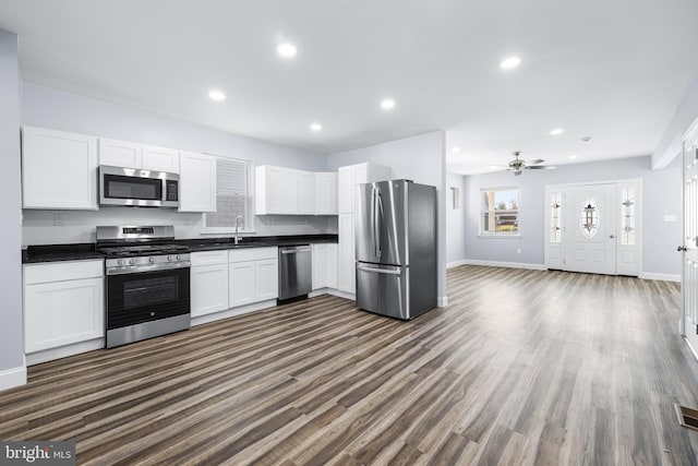 kitchen with dark wood-type flooring, sink, ceiling fan, white cabinetry, and stainless steel appliances