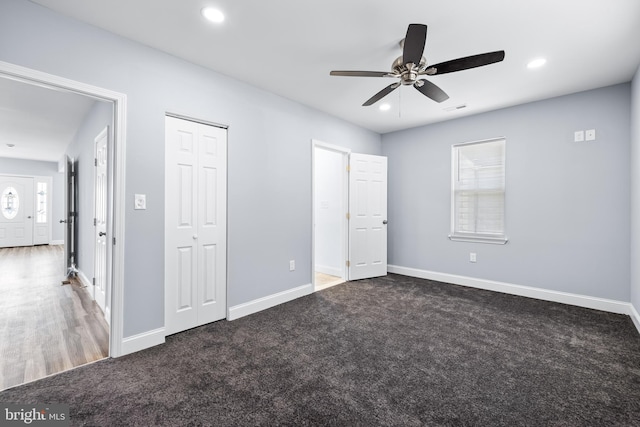 unfurnished bedroom with multiple windows, ceiling fan, and dark carpet