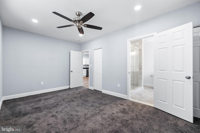 unfurnished bedroom with ensuite bathroom, dark carpet, and ceiling fan