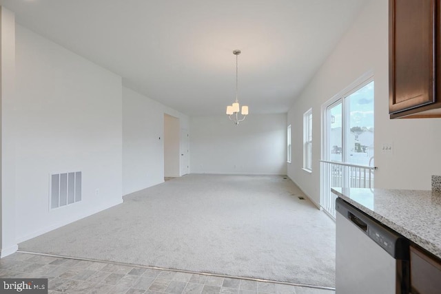 unfurnished dining area with light colored carpet and a notable chandelier