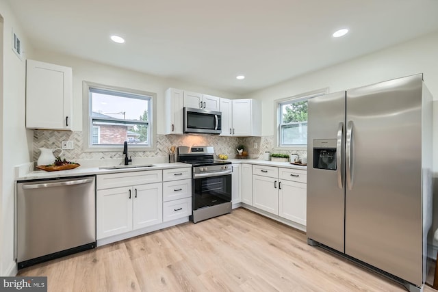 kitchen featuring white cabinets, appliances with stainless steel finishes, light hardwood / wood-style flooring, and sink