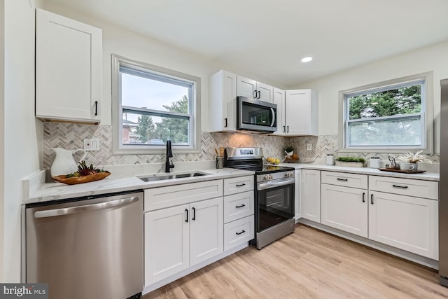 kitchen with white cabinetry, sink, stainless steel appliances, and plenty of natural light