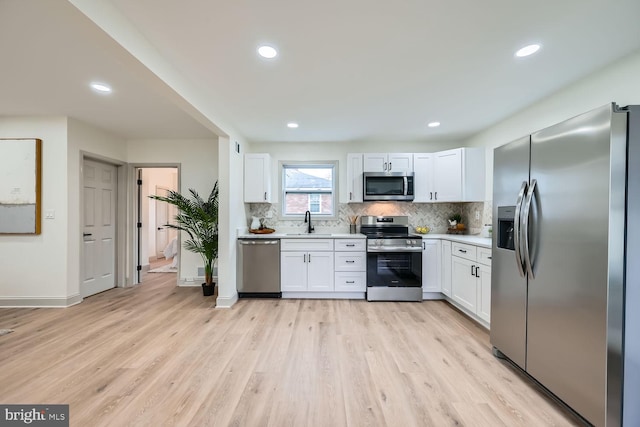 kitchen with sink, decorative backsplash, light wood-type flooring, white cabinetry, and stainless steel appliances