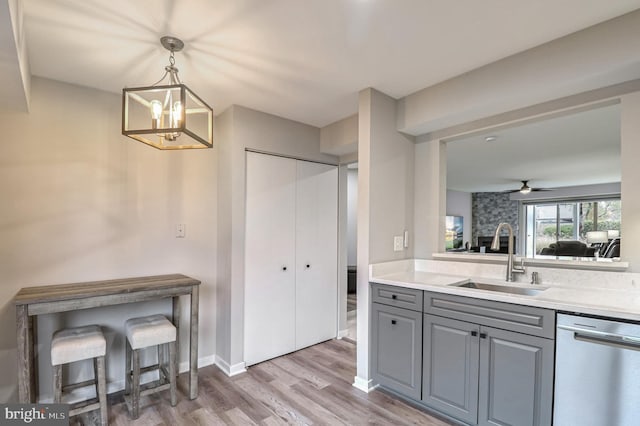 kitchen featuring ceiling fan with notable chandelier, sink, stainless steel dishwasher, gray cabinets, and light hardwood / wood-style floors