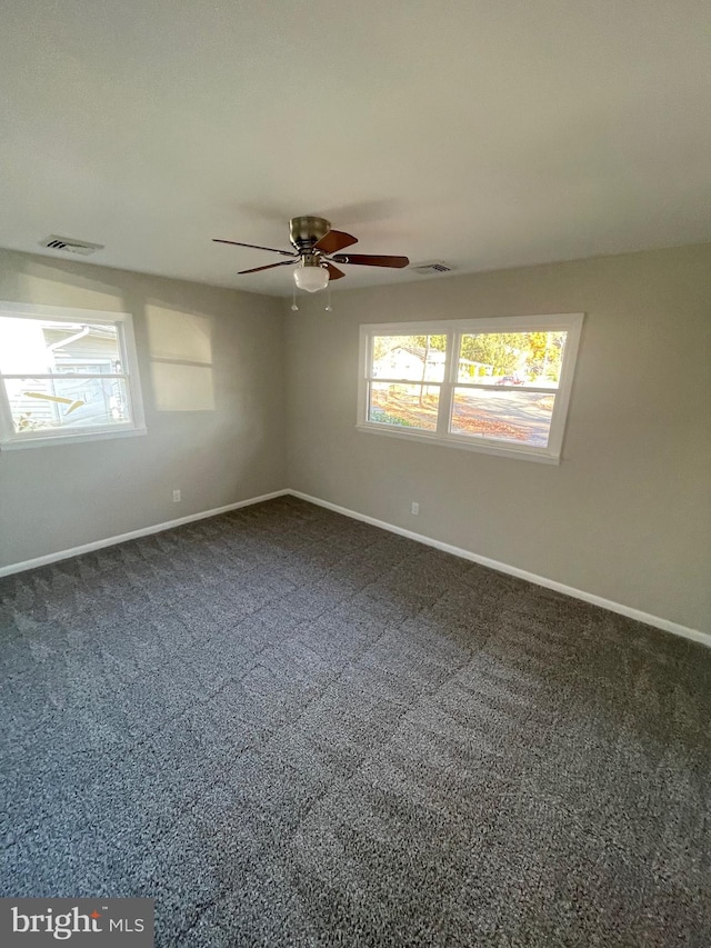 empty room featuring dark colored carpet and ceiling fan