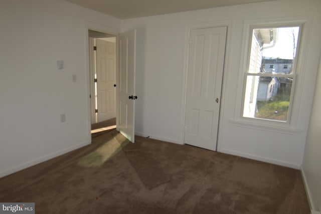 unfurnished bedroom with dark colored carpet