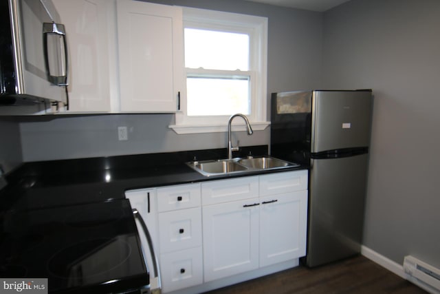 kitchen with appliances with stainless steel finishes, baseboard heating, dark wood-type flooring, sink, and white cabinets