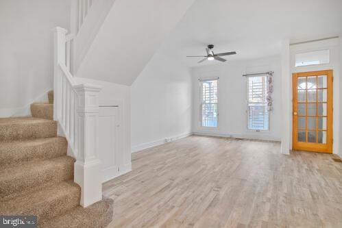 unfurnished living room with light hardwood / wood-style floors, an AC wall unit, ceiling fan, and lofted ceiling