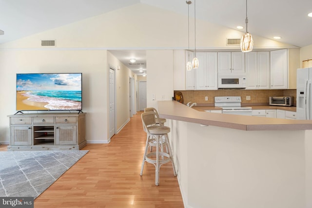 kitchen featuring white cabinetry, light hardwood / wood-style flooring, kitchen peninsula, white appliances, and a breakfast bar