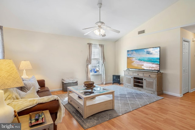 living room with a wood stove, ceiling fan, wood-type flooring, and lofted ceiling