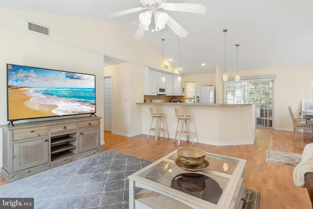 living room with ceiling fan, light hardwood / wood-style floors, and high vaulted ceiling