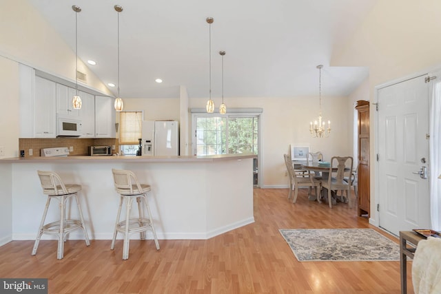 kitchen featuring light hardwood / wood-style floors, decorative light fixtures, white cabinetry, and white appliances